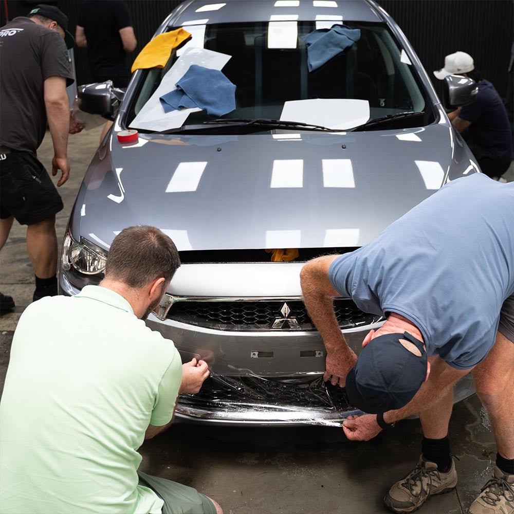 Students applying PPF on a silver car