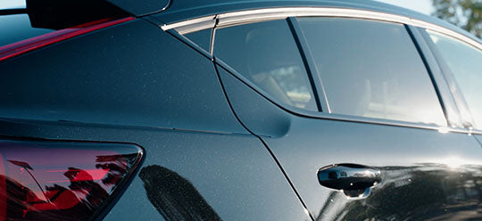 Side of a black car reflecting in light