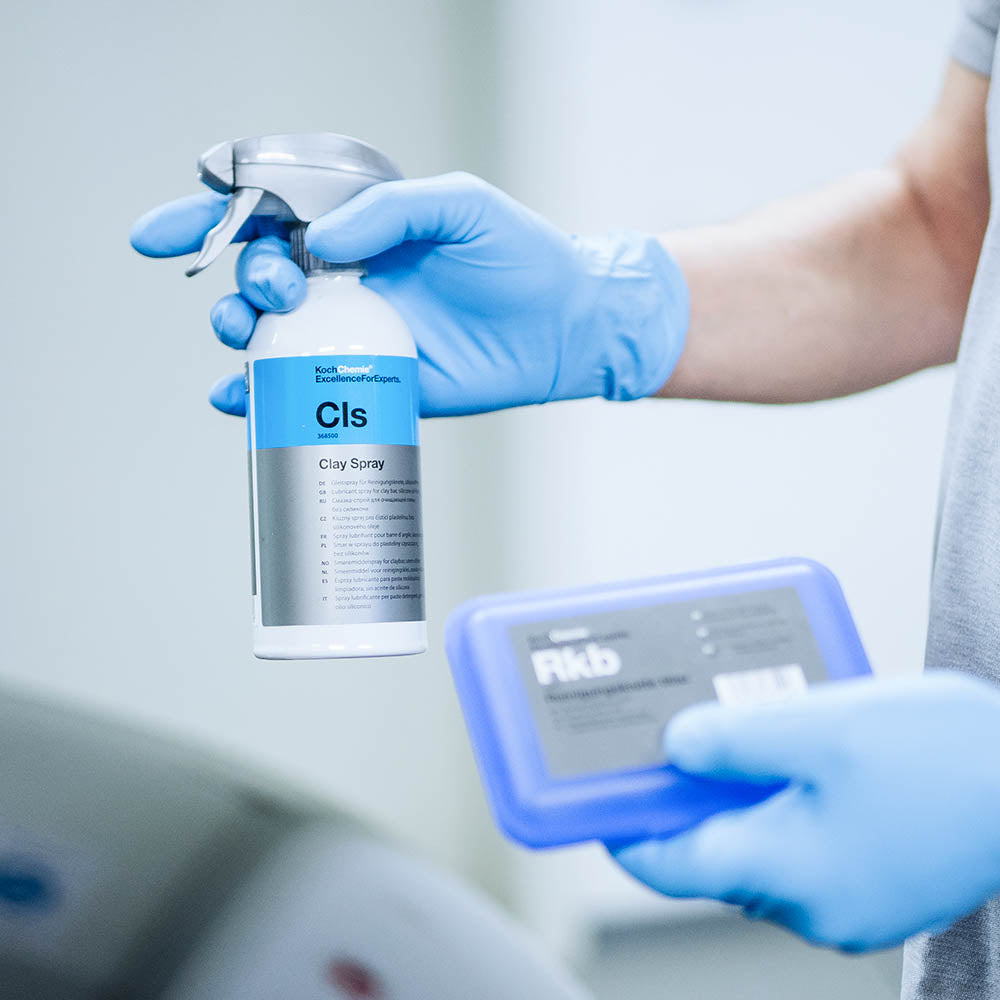 Koch Chemie Clay Spray 500 mL bottle held alongside a Koch Chemie clay bar
