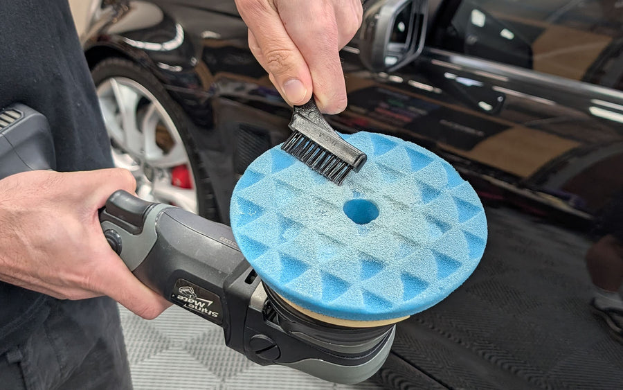 Brushing a foam polishing pad clean