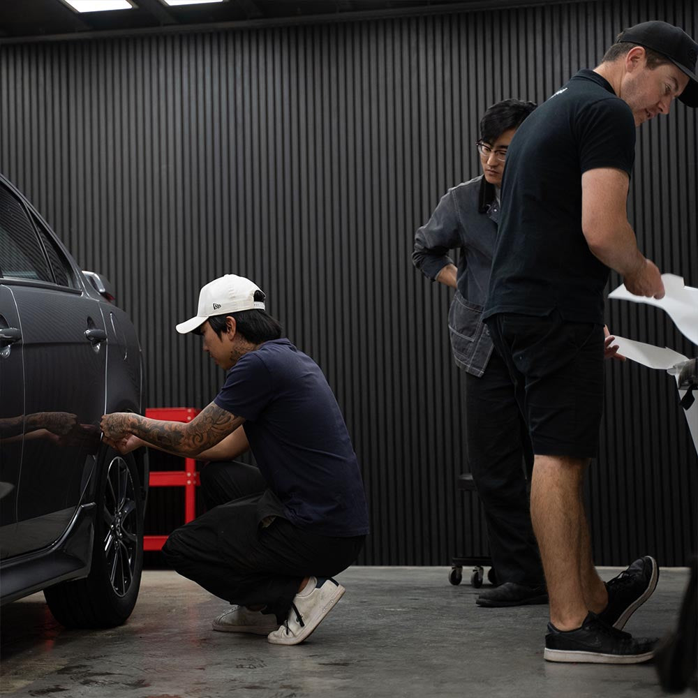 Students applying PPF to silver car