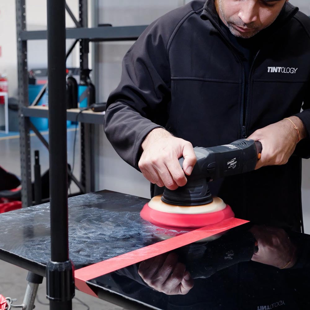 student polishing a black panel with a shinemate