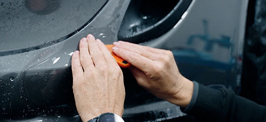 A person applying PPF using a squeege