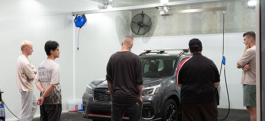 A group detailing class inspecting a car