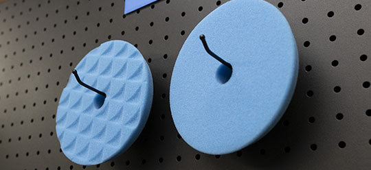 2 Blue ShineMate Pads hanging on a wall. 